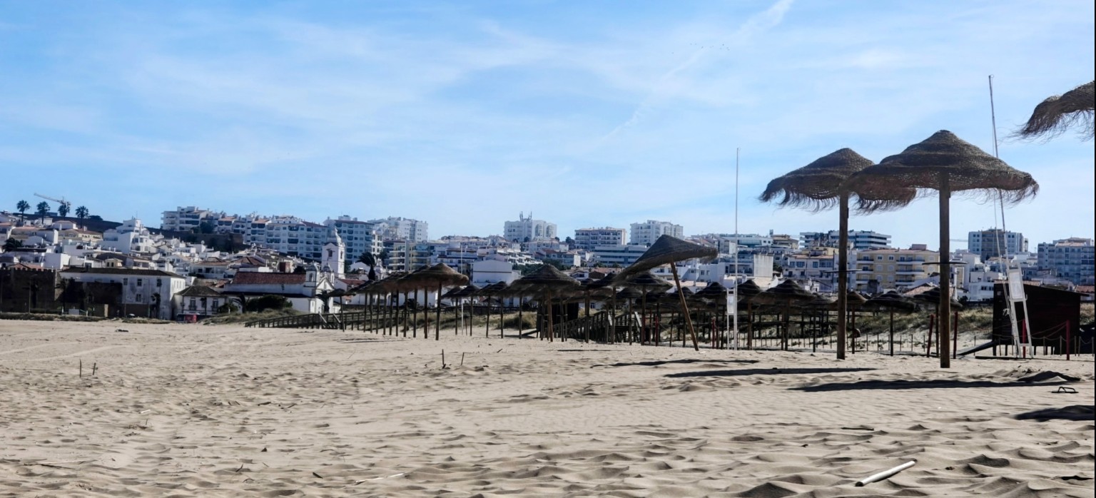 Sonnenschirme an der Meia Praia mit Lagos im Hintergrund